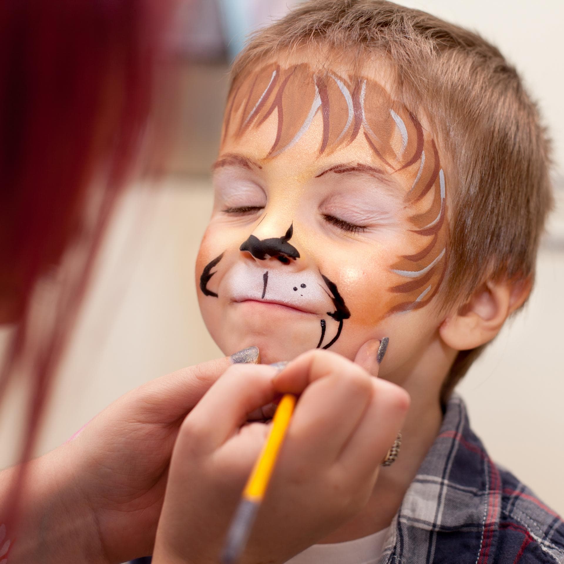 Kleiner Junge, dem ein Löwengesicht geschminkt wird.
