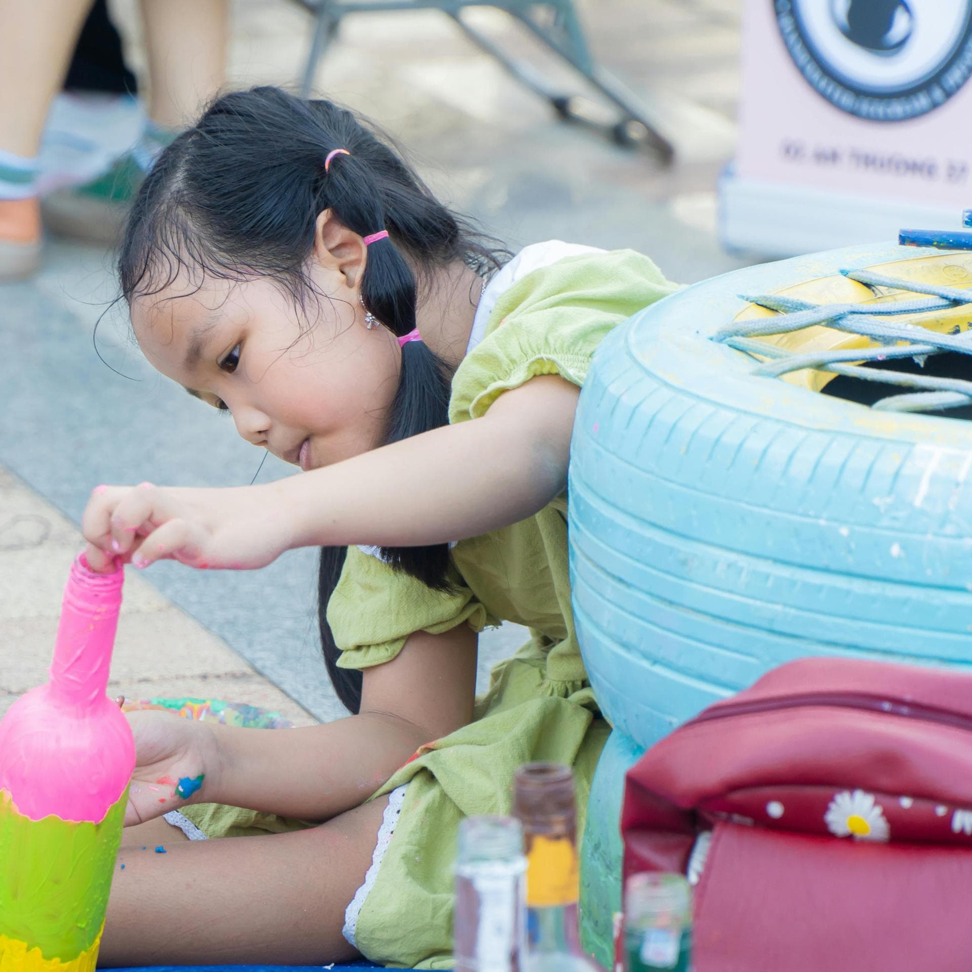 Mädchen bemalt Flasche bunt.