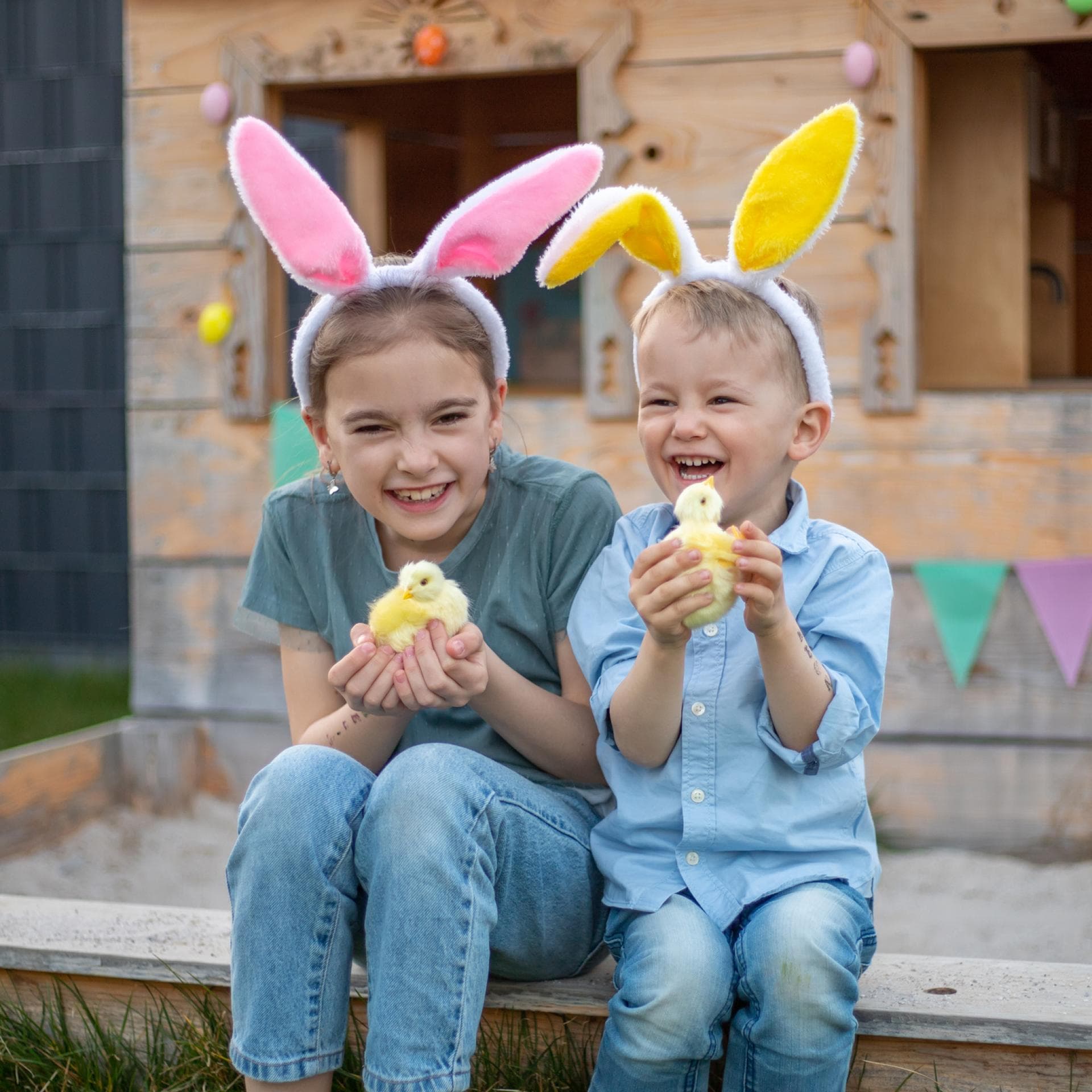 Zwei Kinder mit Osterhasenohren und einem Küken in der Hand