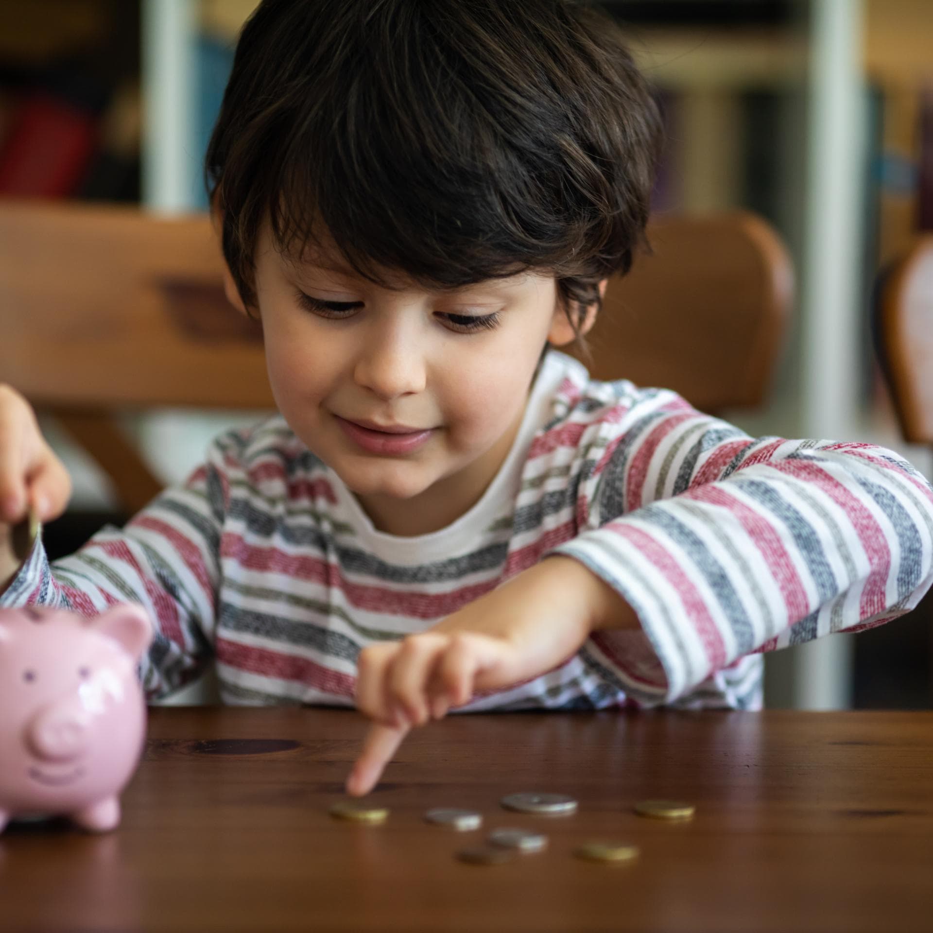 Junge steckt Geld in sein Sparschwein.