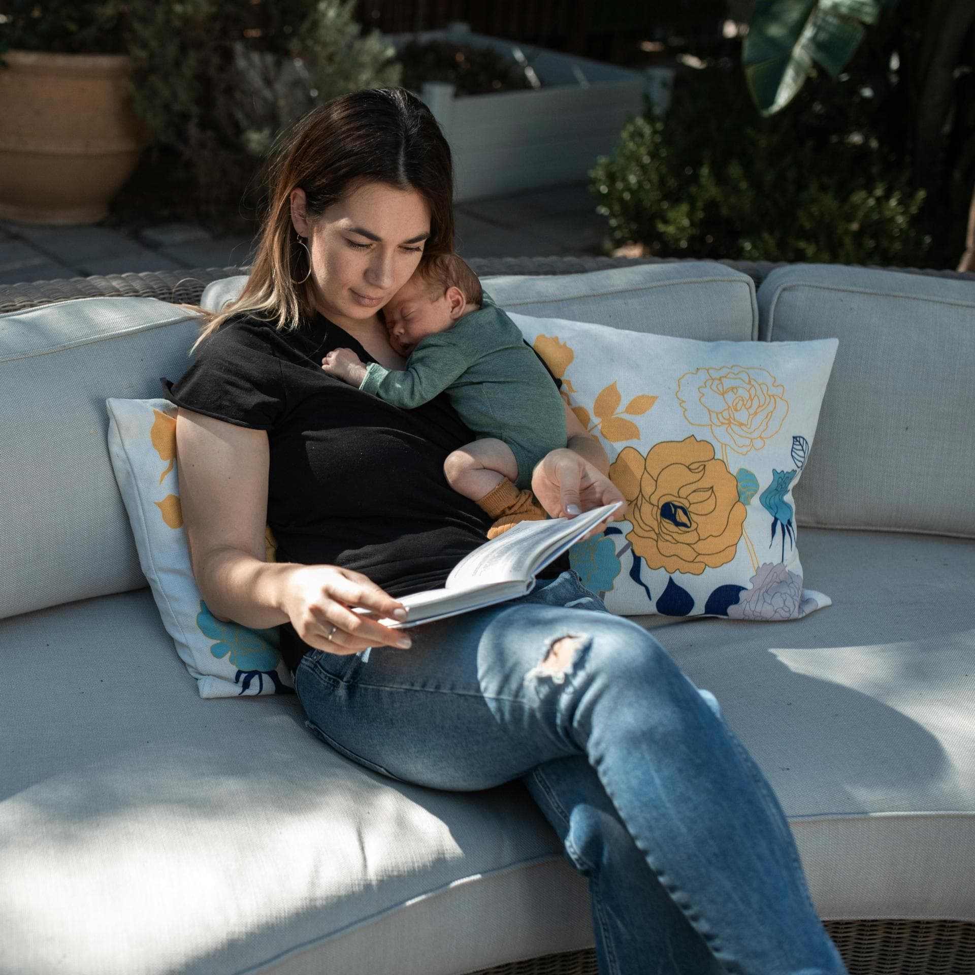 Mama sitzt mit Baby draußen auf Sofa.