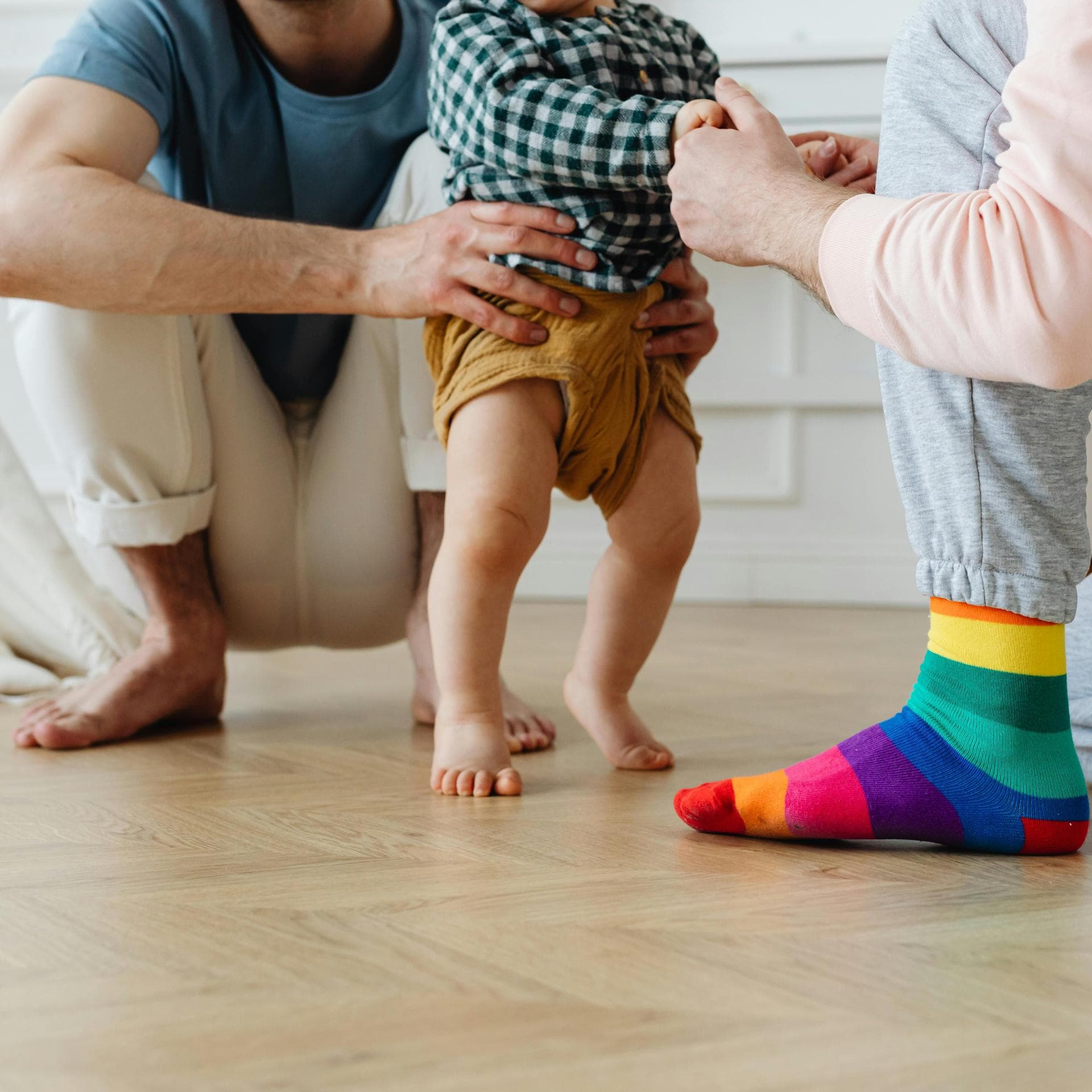 Baby läuft barfuß mit Hilfe von einem zum anderen.