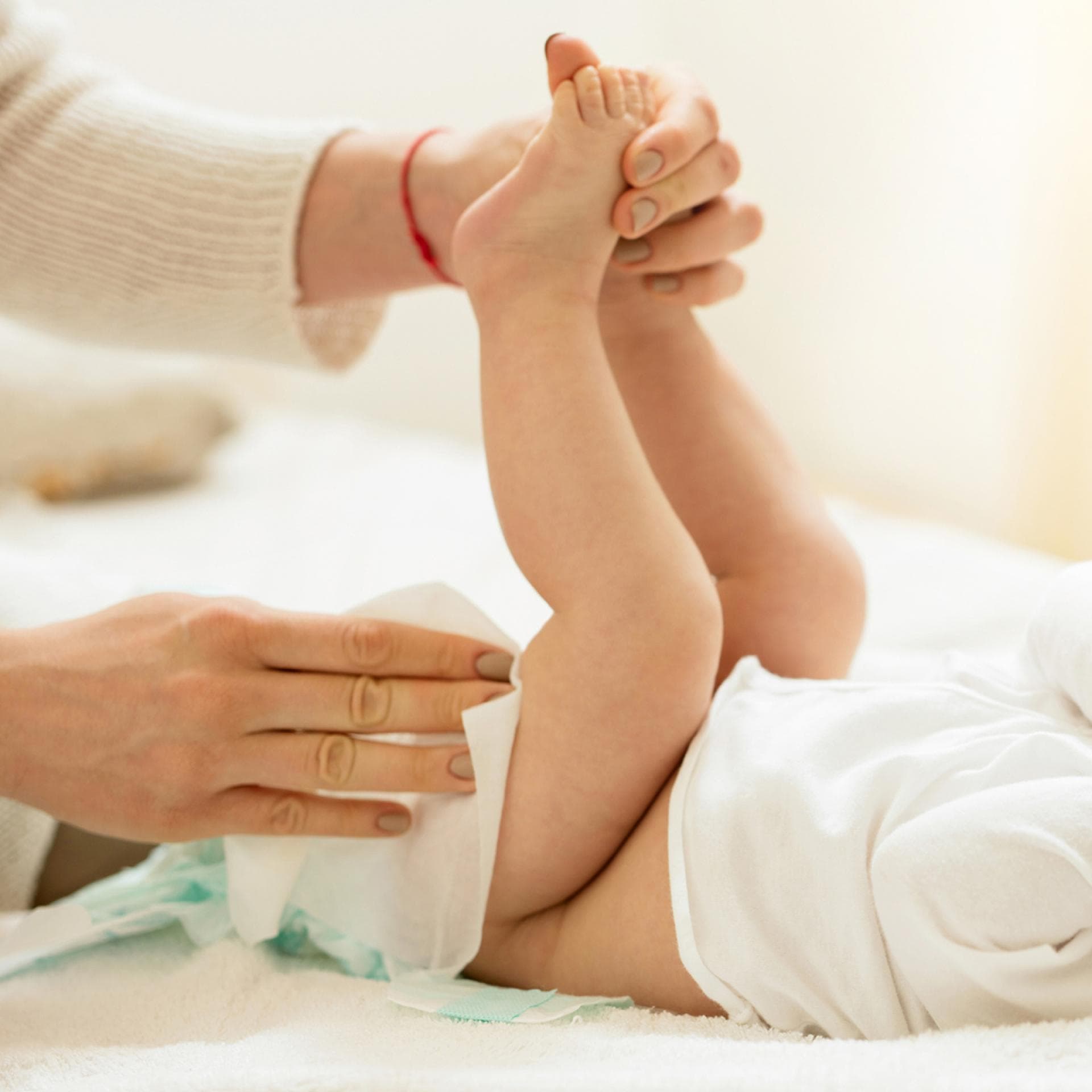 Eine Mutter wechselt ihrem Baby die Windel. 