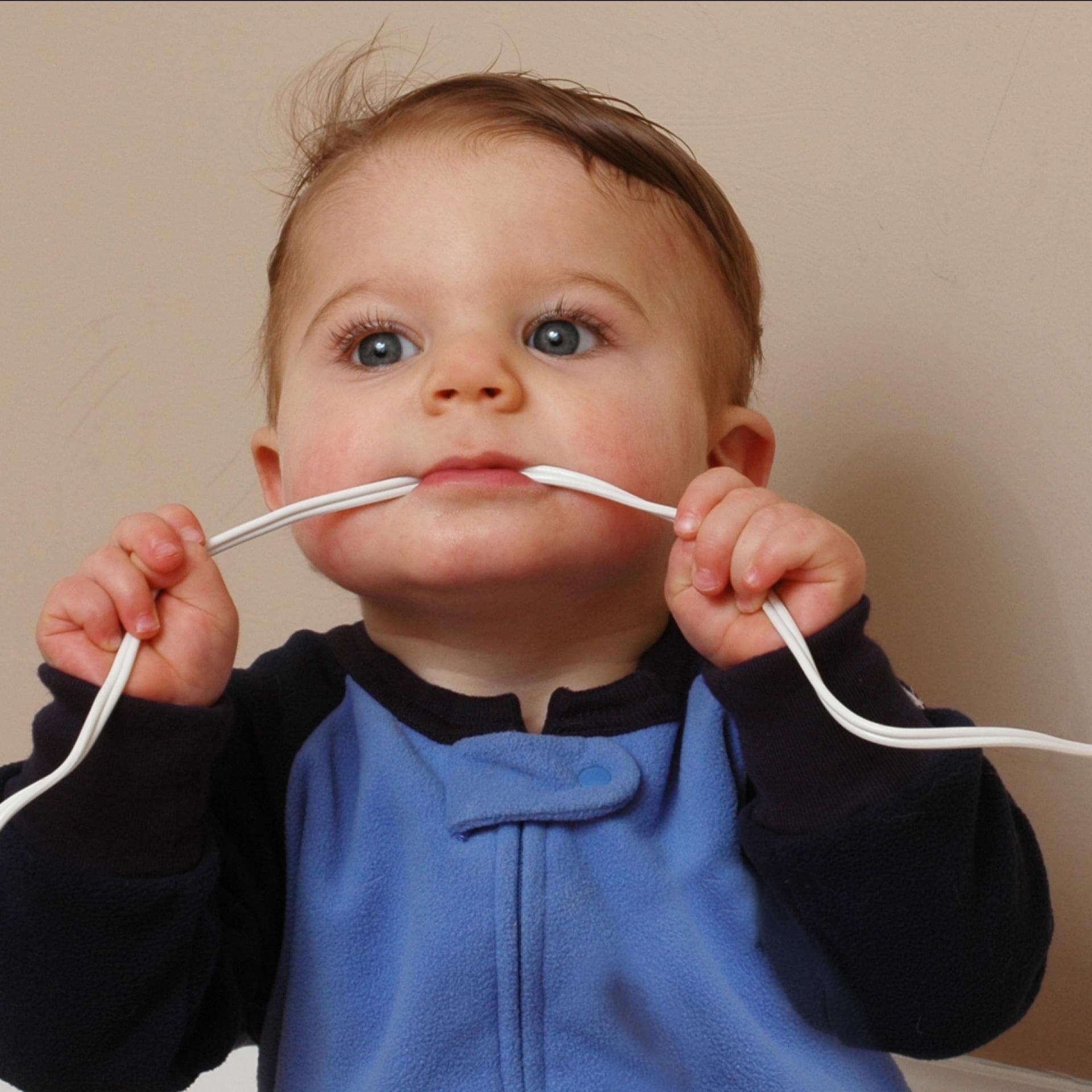 Ein Baby nimmt ein Ladekabel in den Mund. 