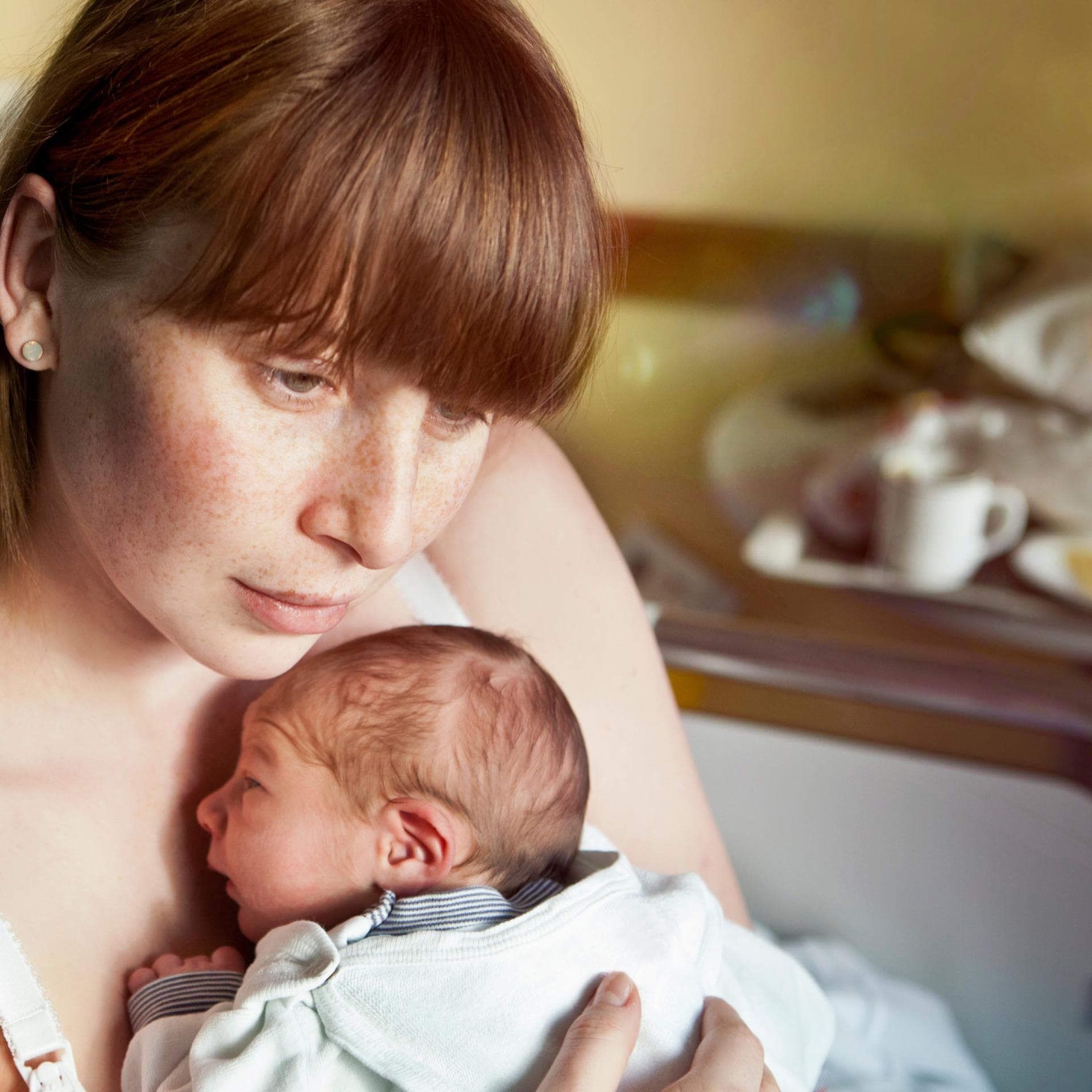 Verträumte Mutter hält Neugeborenes auf dem Arm.