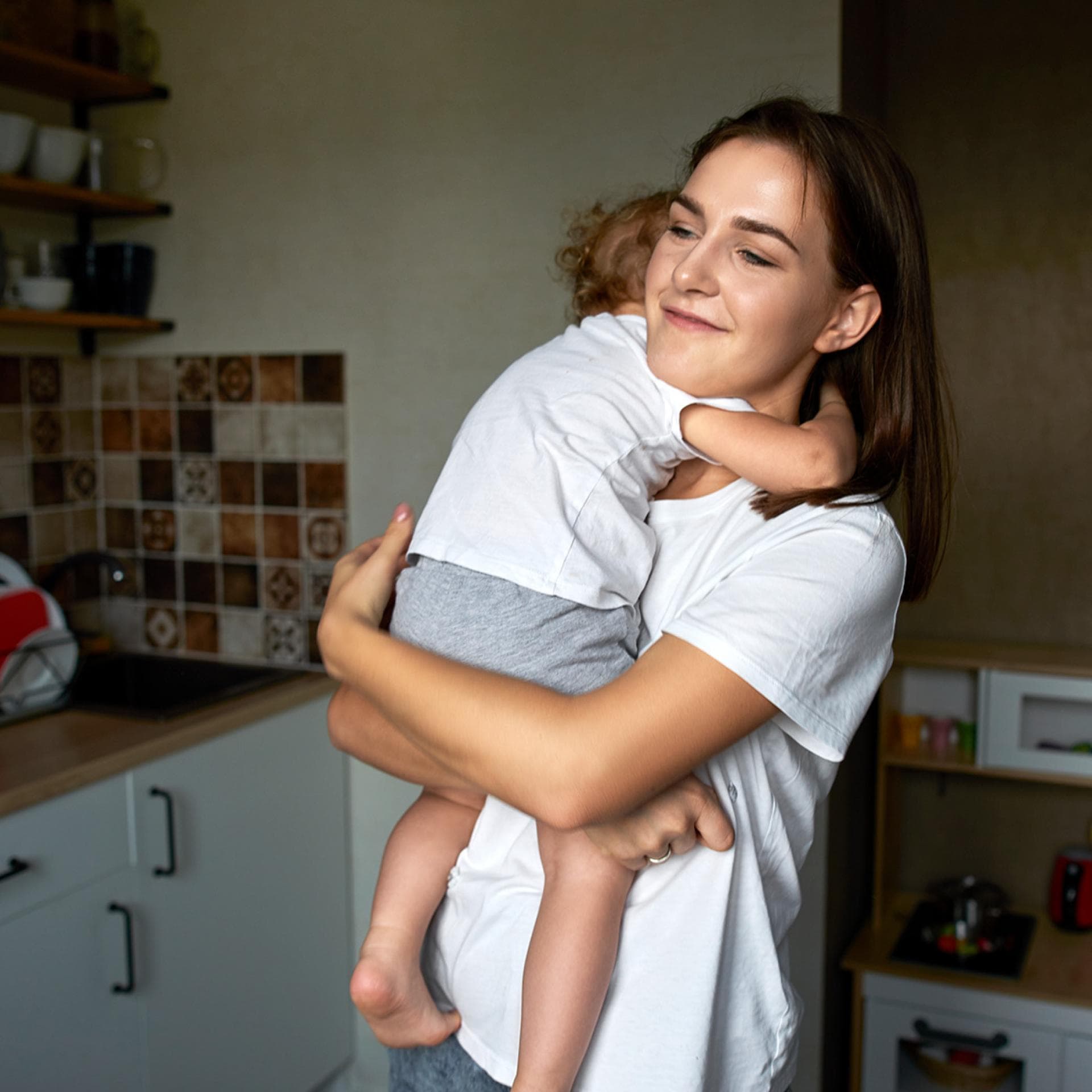 Mama und Kleinkind umarmen sich.