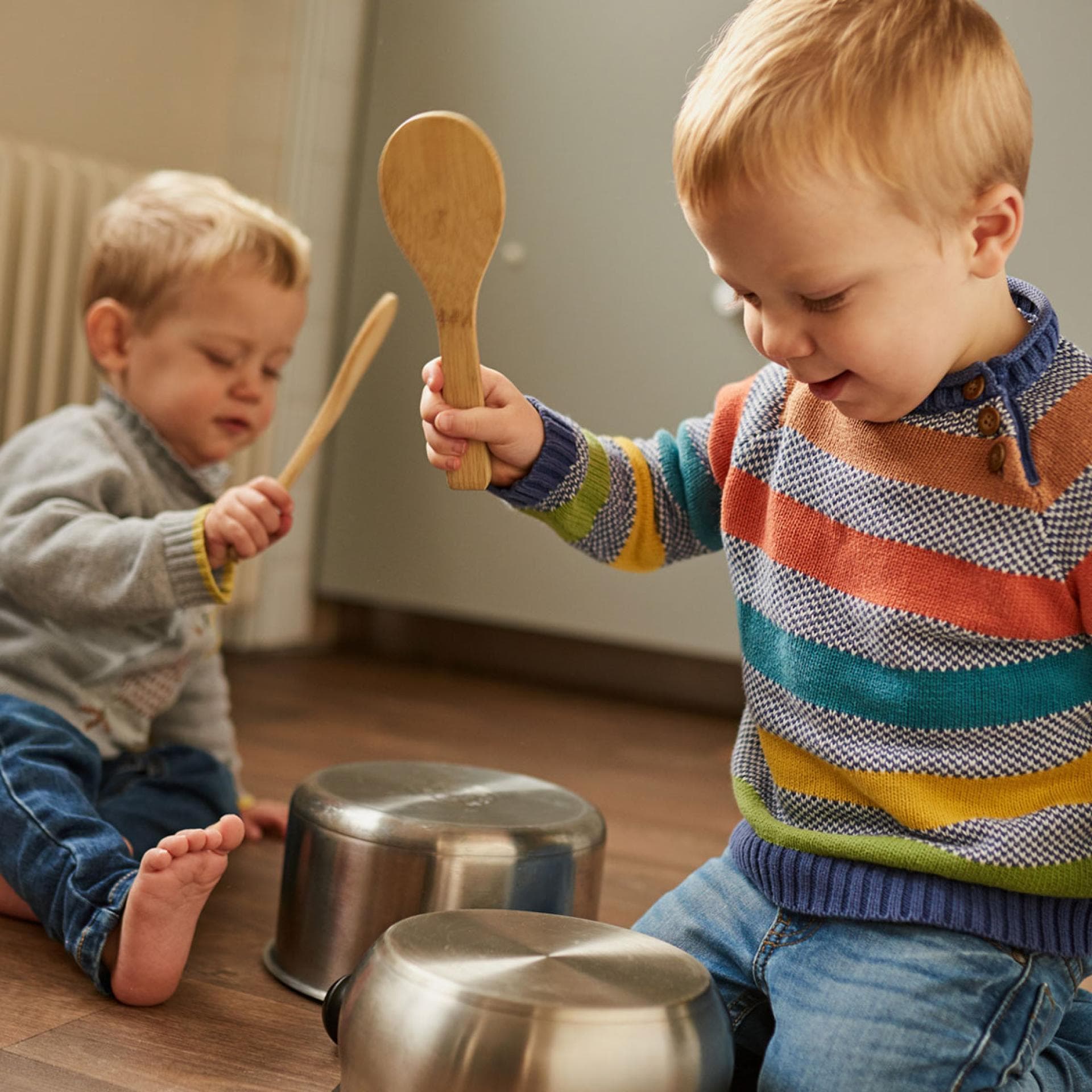 Kinder schlagen mit Kochlöffeln auf Töpfe.