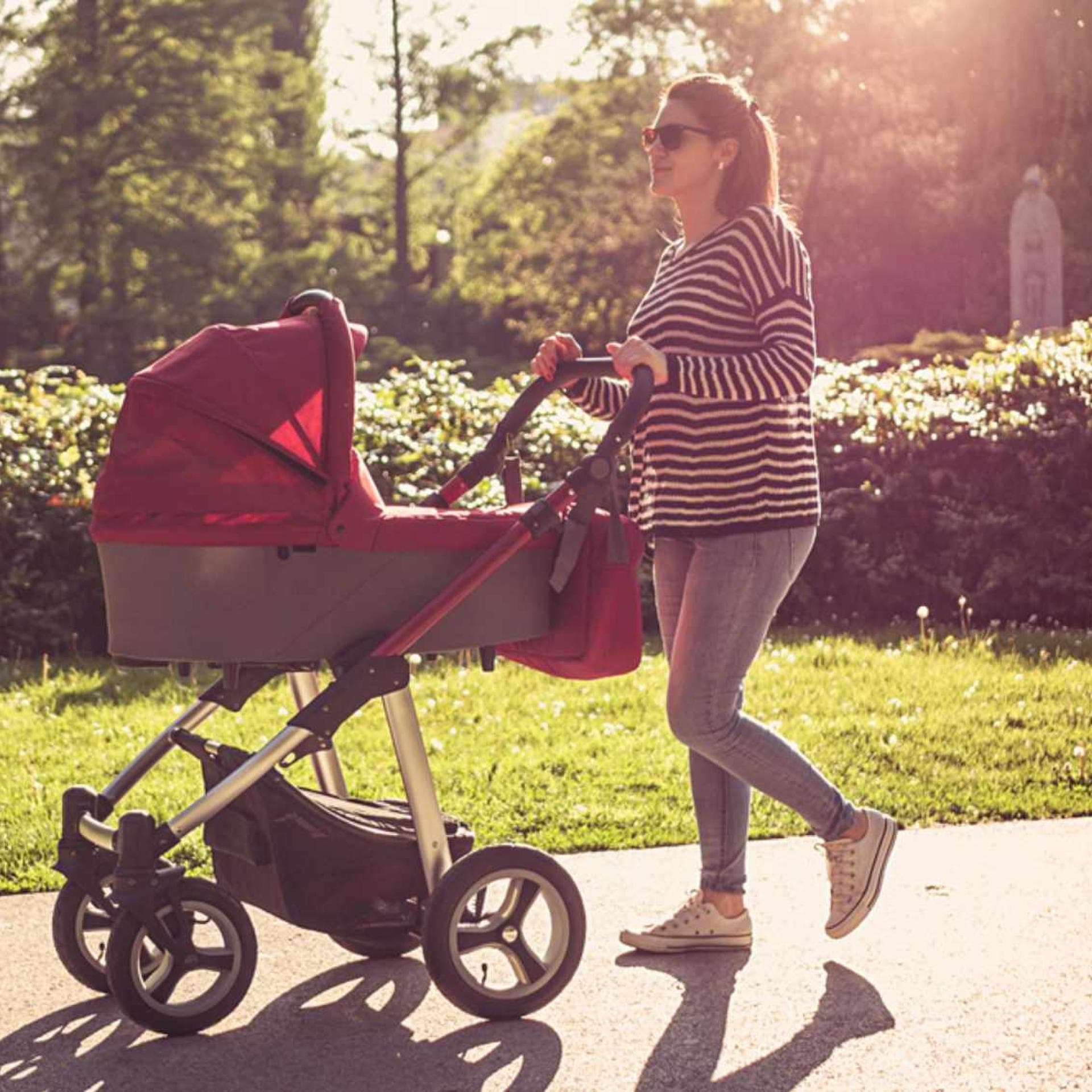 Mutter geht mit Kinderwagen spazieren.