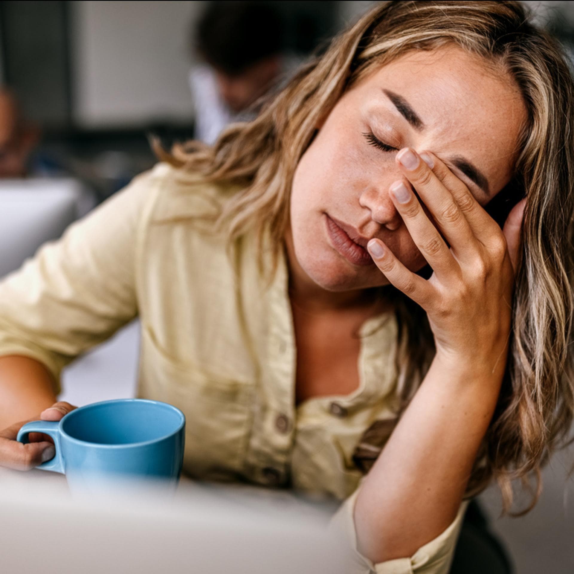 Erschöpfte Frau mit Kaffeebecher.