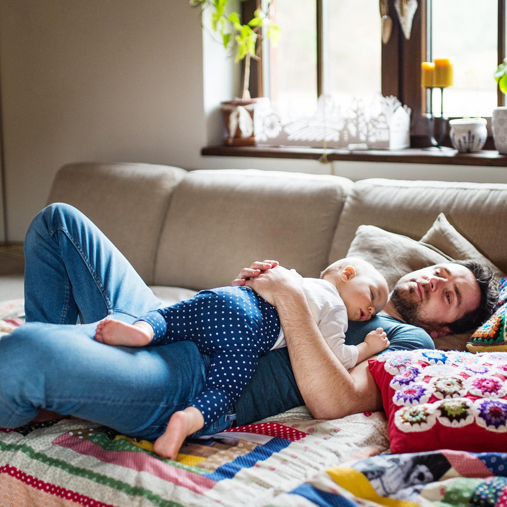 Baby und Papa liegen schlafend auf dem Sofa.