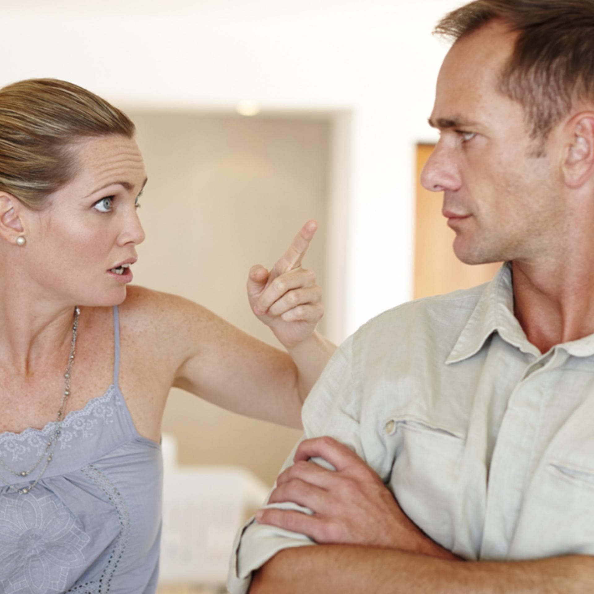 Mutter mit Baby auf dem Arm spricht belehrend mit ihrem Mann.