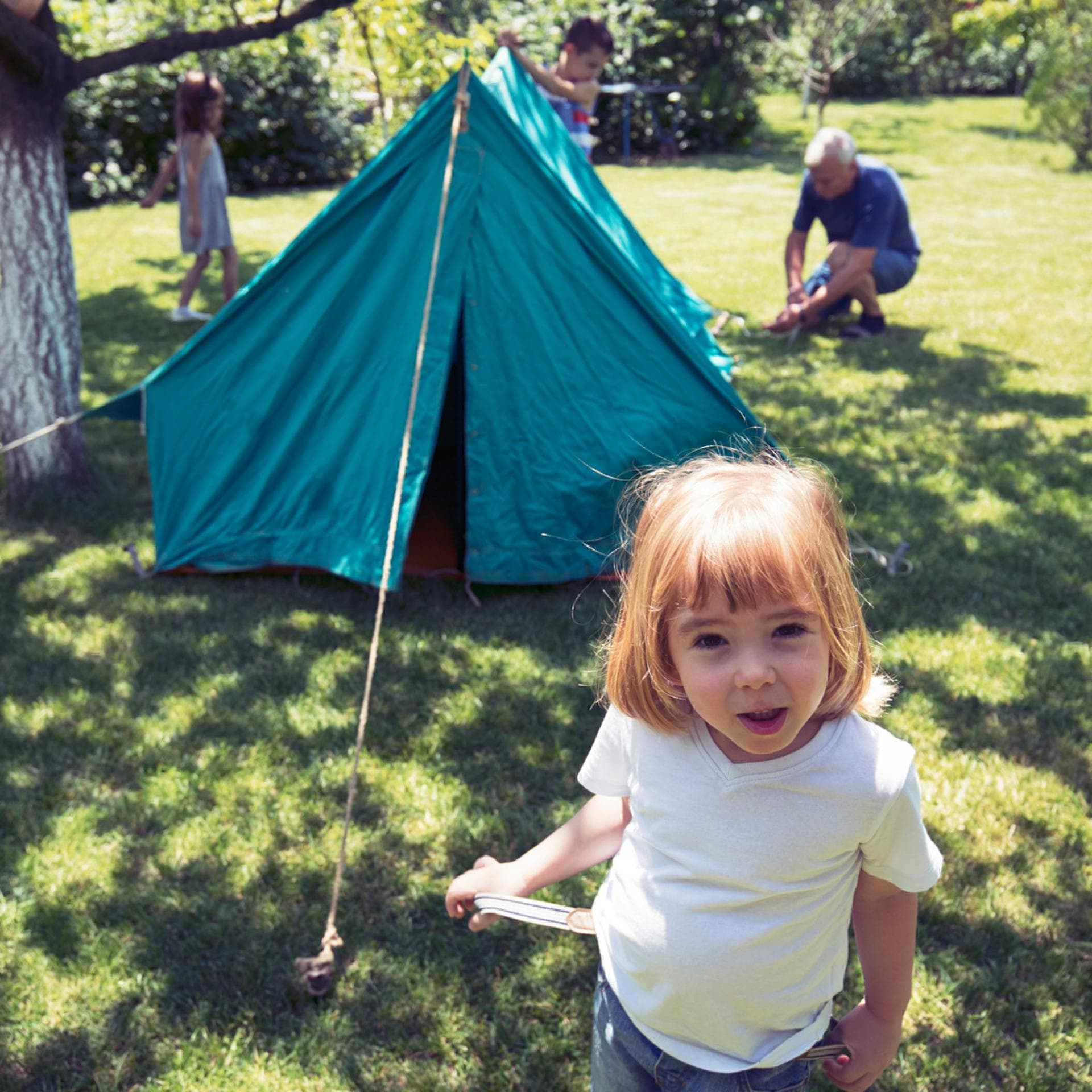 Familie baut ein Zelt im Garten auf.
