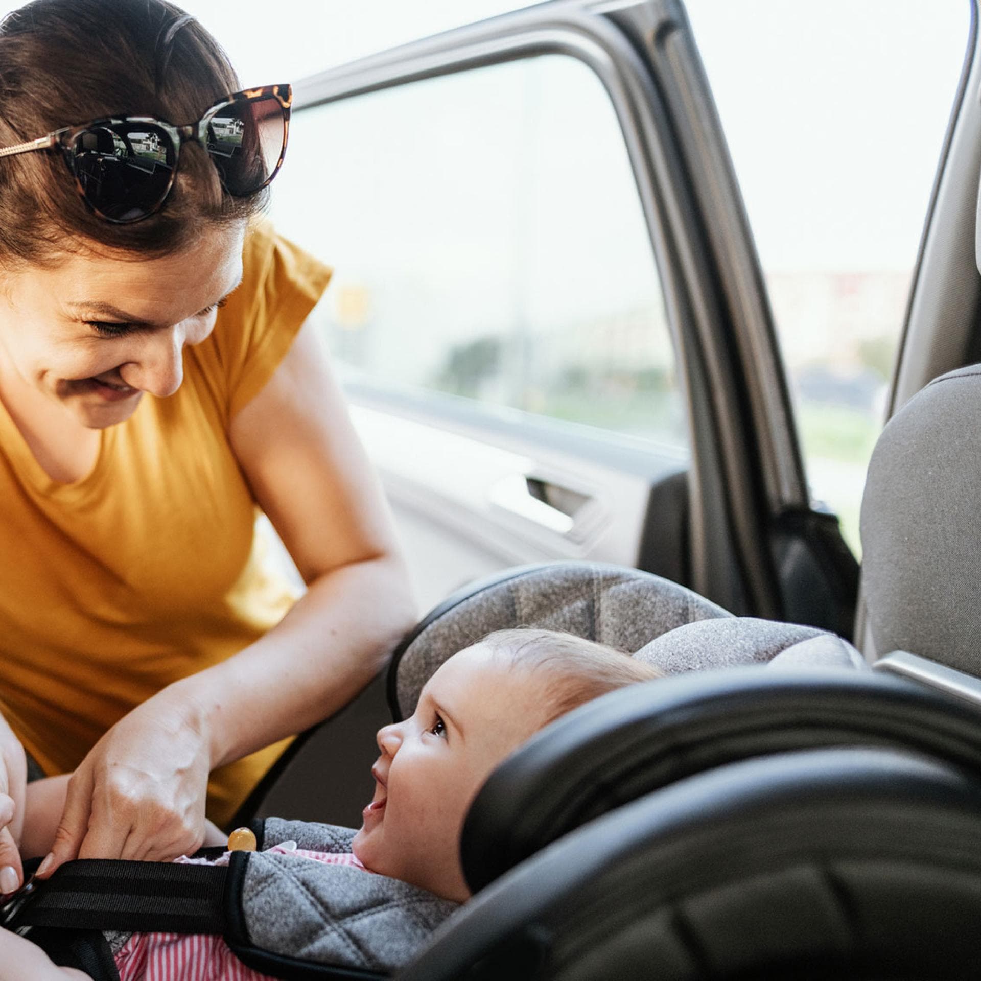 Eine Mutter schnallt ihr Baby im Auto an. 