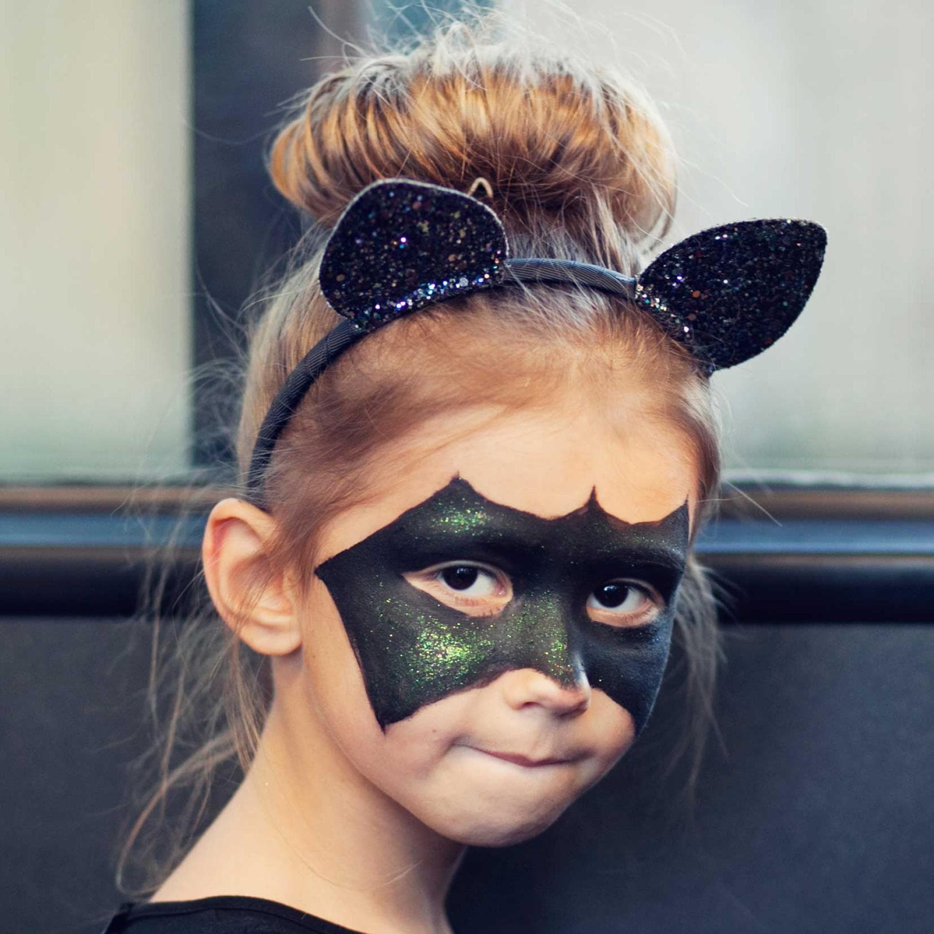 Mädchen als Fledermaus geschminkt.