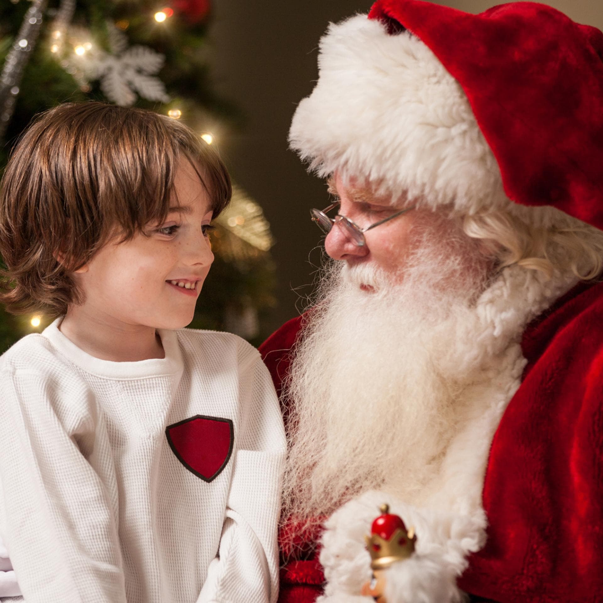 Kind sitzt auf dem Schoß vom Nikolaus oder Weihnachtsmann.