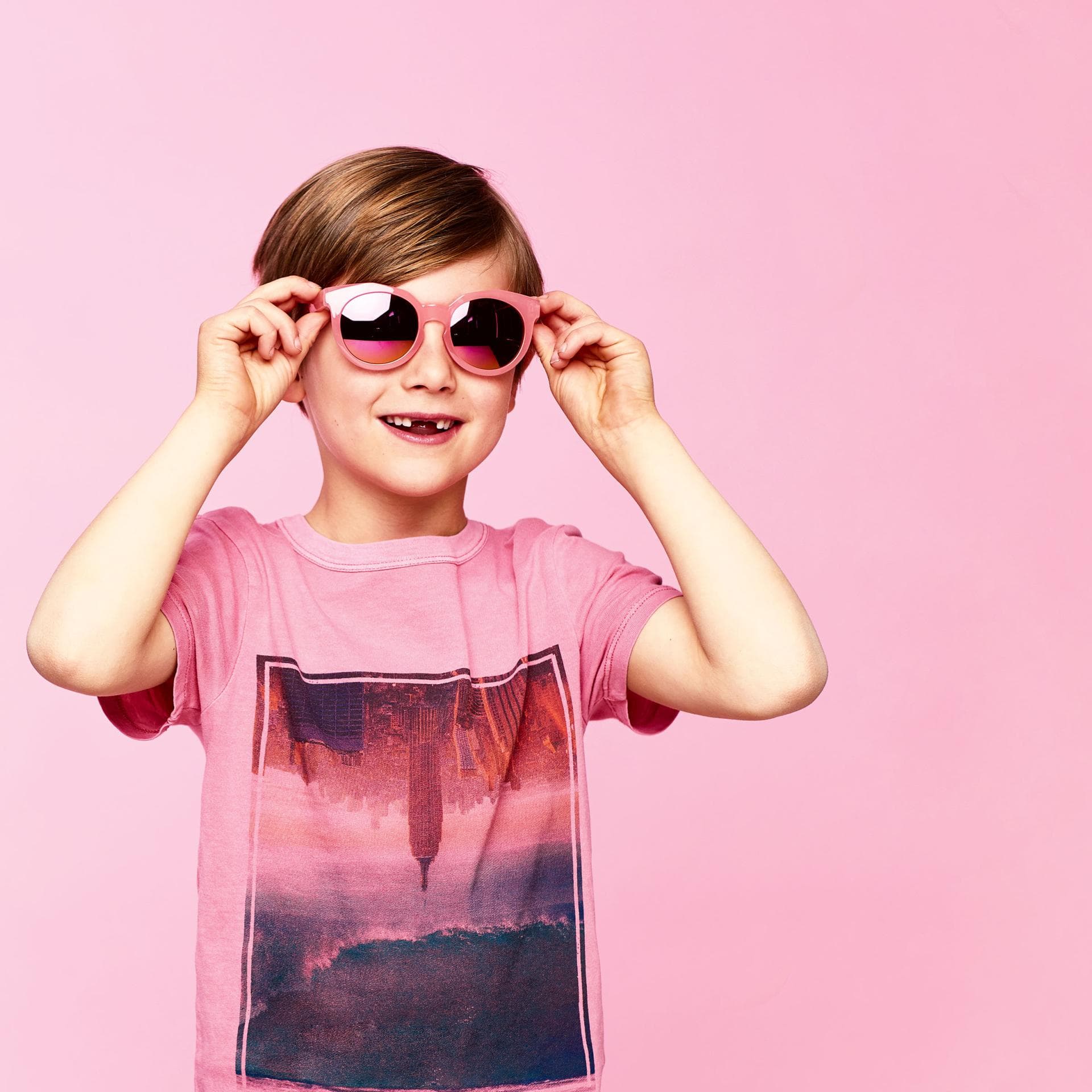 Junge mit rosa T-Shirt und rosa Sonnenbrille.