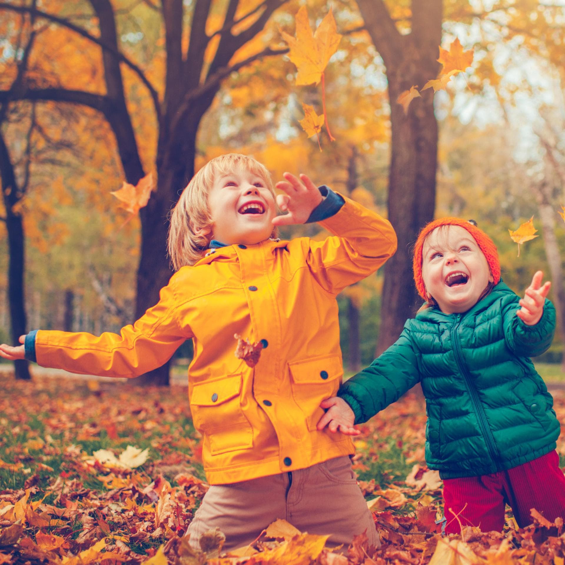 Zwei Kinder freuen sich über buntes Herbstlaub.