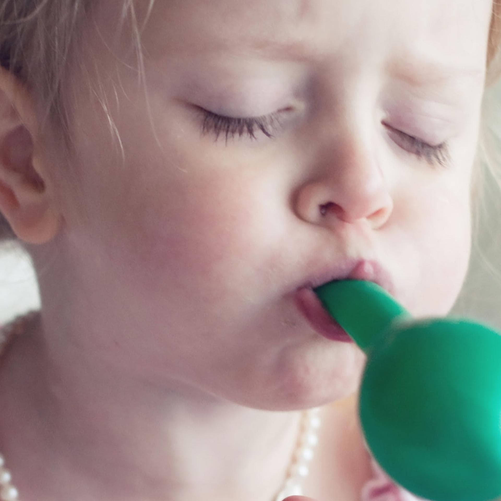 Mädchen pustet einen Luftballon auf.