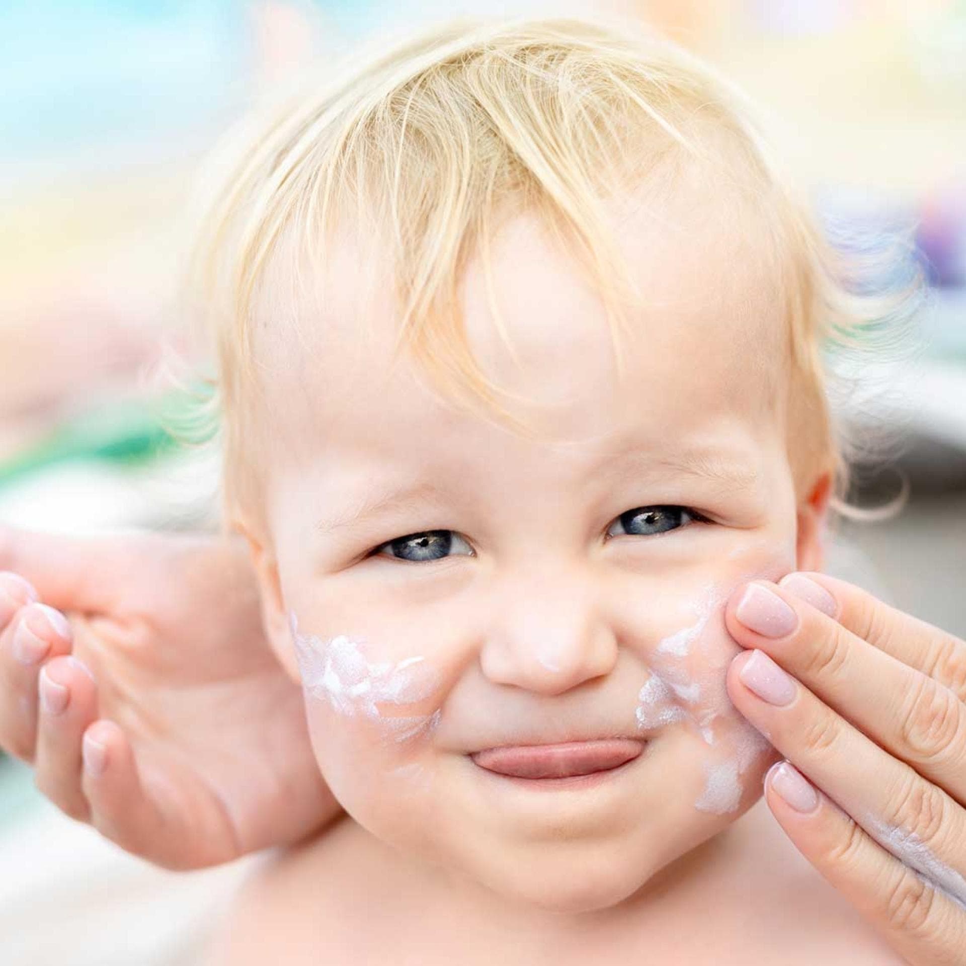 Baby wird mit Sonnencreme eingeschmiert.