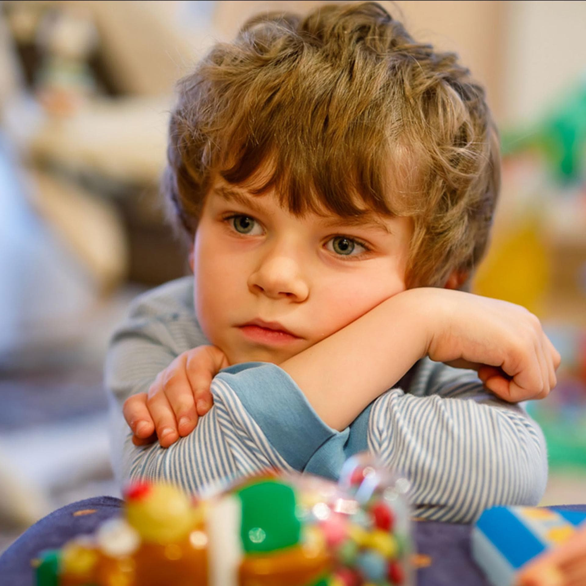 Ein unglücklich schauender Junge sitzt alleine in der Kita..