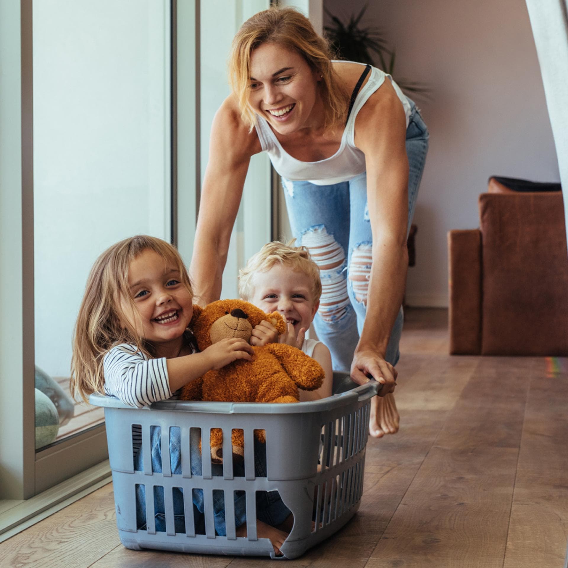 Mutter schiebt ihre Kinder im Wäschekorb.