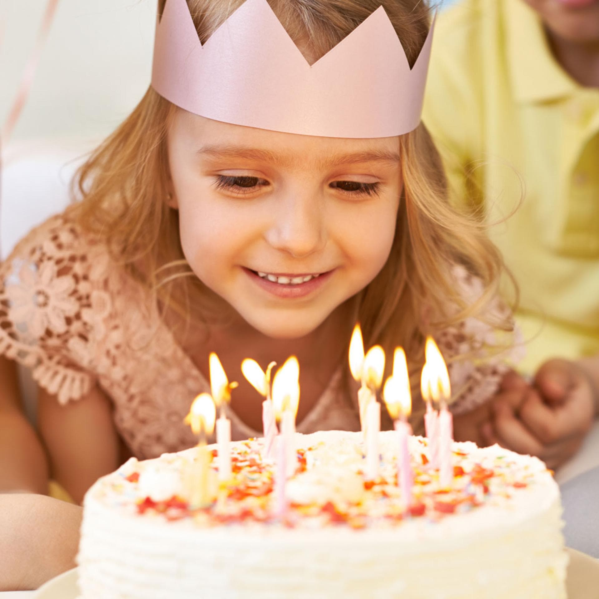 Ein Mädchen bläst die Kerzen auf ihrem Geburtstagskuchen aus. 