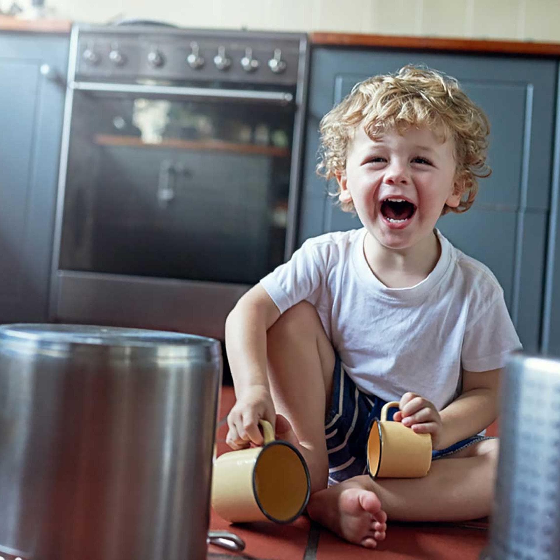 Kleinkind spielt fröhlich in der Küche mit Geschirr und Töpfen