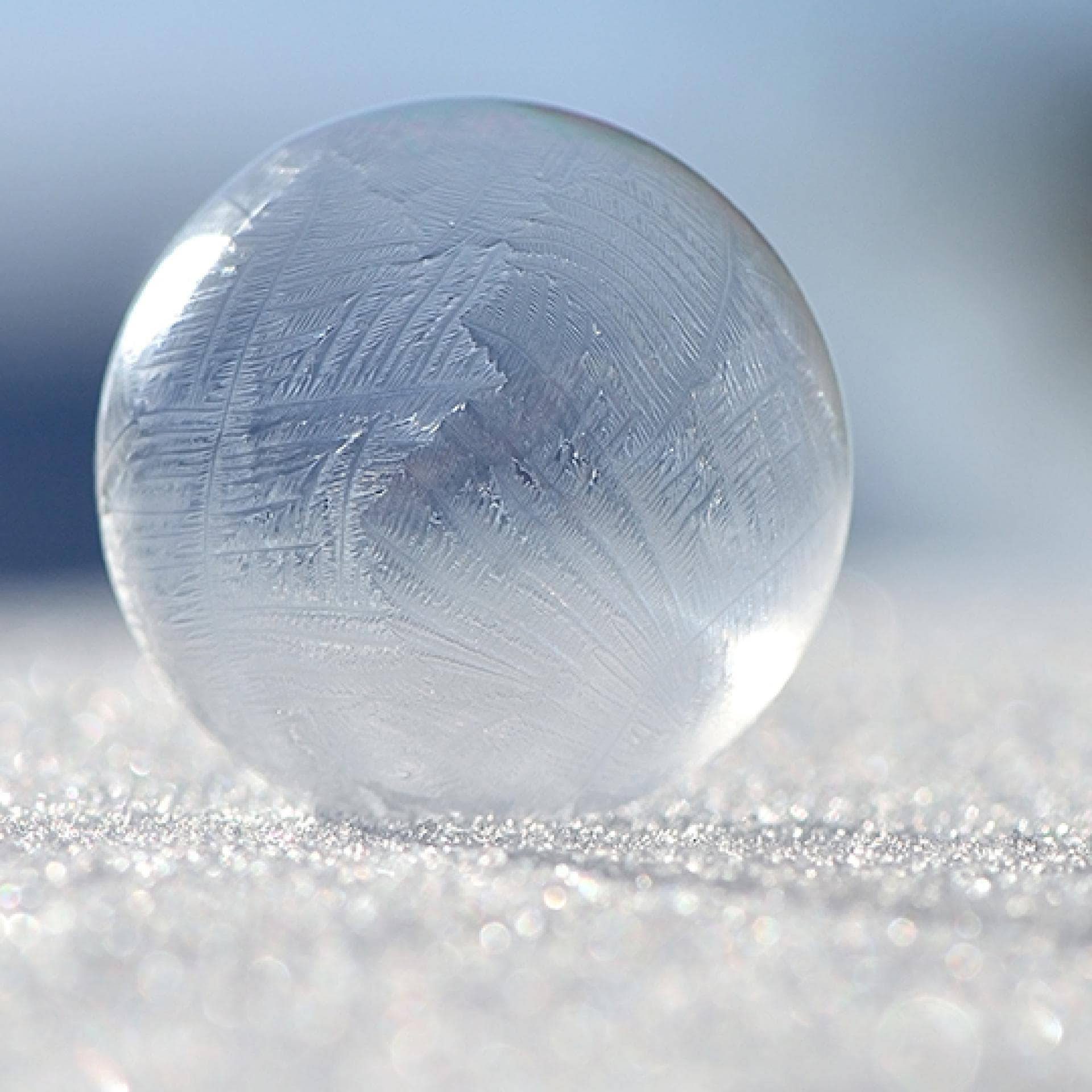 Eine gefrorene Seifenblase liegt auf einer Eisfläche.