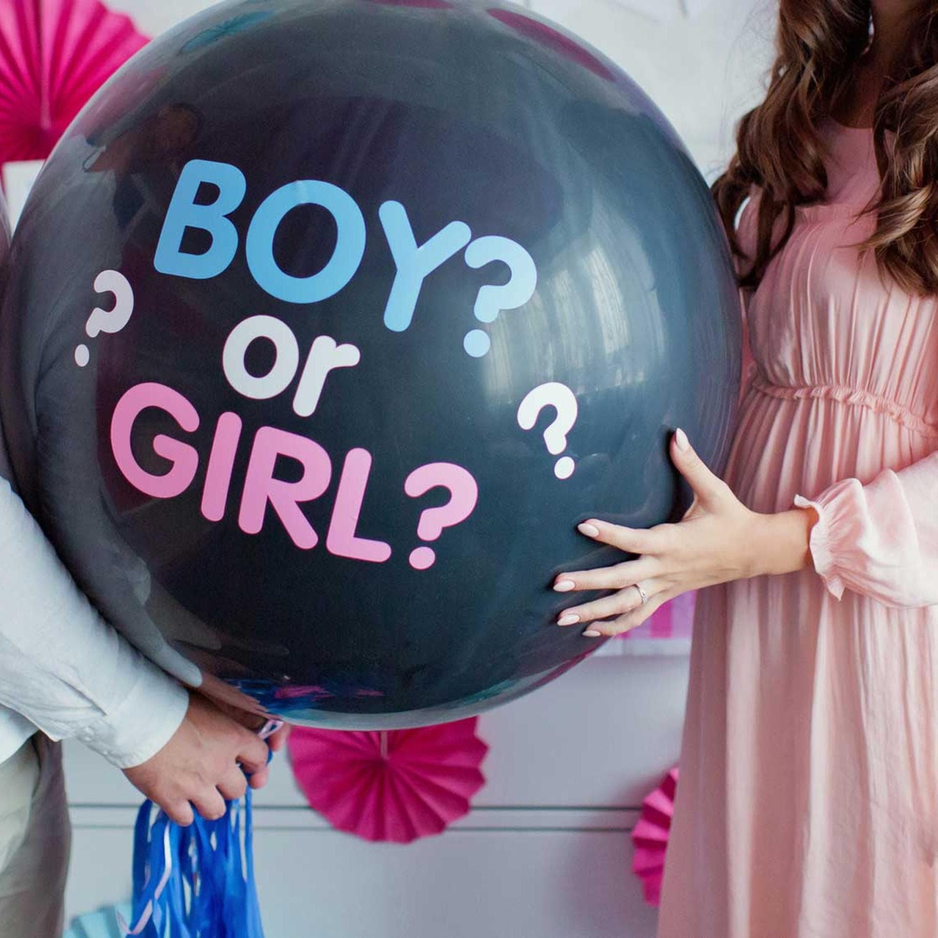 Werdende Eltern halten großen Ballon mit Aufschrift "boy or girl?".