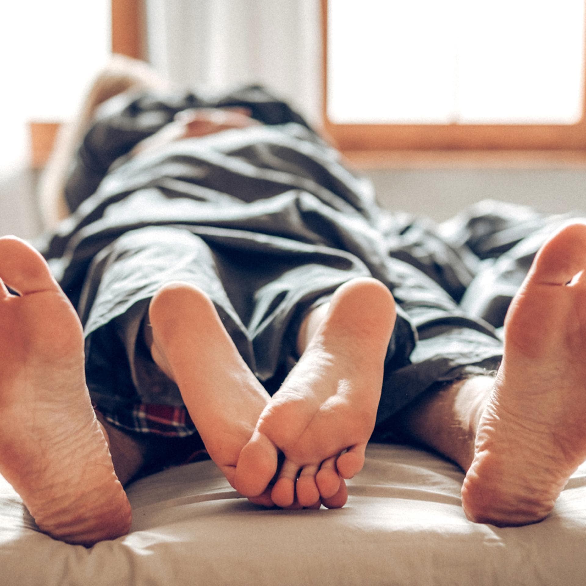 Paar liegt unter dem Laken aufeinander, die Füße schauen heraus.