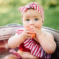 Ein Baby sitzt draußen in einer Badeschale.
