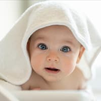Ein Baby versteckt sich unter einem Handtuch.