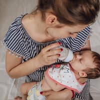 Eine junge Frau füttert ihr Baby mit der Flasche