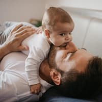 Ein Baby liegt auf dem Bauch seines Vaters.