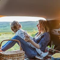 Mutter und Kind sitzen im Van und haben ein Picknick dabei.