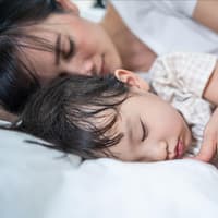 Sohn und Mama schlafen in einem Bett.