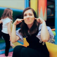 Frau hält sich auf einem Spielplatz die Ohren zu