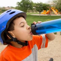 Junge trinkt im Freien aus seiner blauen Trinkflasche – doch wie reinigt man die am besten?