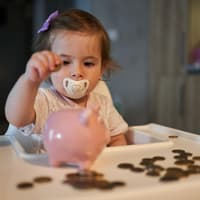 Kleinkind wirft Geld ins Sparschwein.