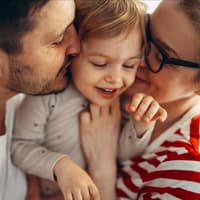 Glückliche Eltern kuscheln mit ihrer Tochter.