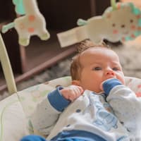 Baby liegt in elektrischer Babywippe