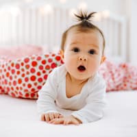 Baby mit erstauntem Gesichtsausdruck im Bett.