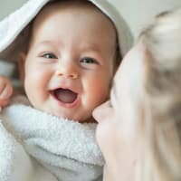 Lachendes Baby unter einem Handtuch.