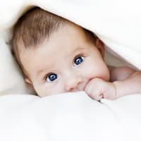 Baby guckt unter Decke hervor.