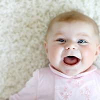 Baby-Mädchen mit biblischem Namen lacht fröhlich in die Kamera. 
