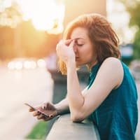 Frau gestresst mit Handy in der Hand