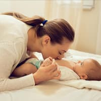 Mama kuschelt mit Baby beim Wickeln