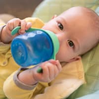 Ein Baby trinkt an seinem besten Trinklernbecher