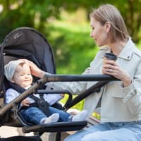 Eine Mutter streichelt ihr Baby im Kinderwagen über den Kopf.