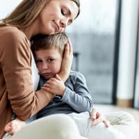 Liebevolle Mutter, die ihren traurigen Sohn zu Hause tröstet.